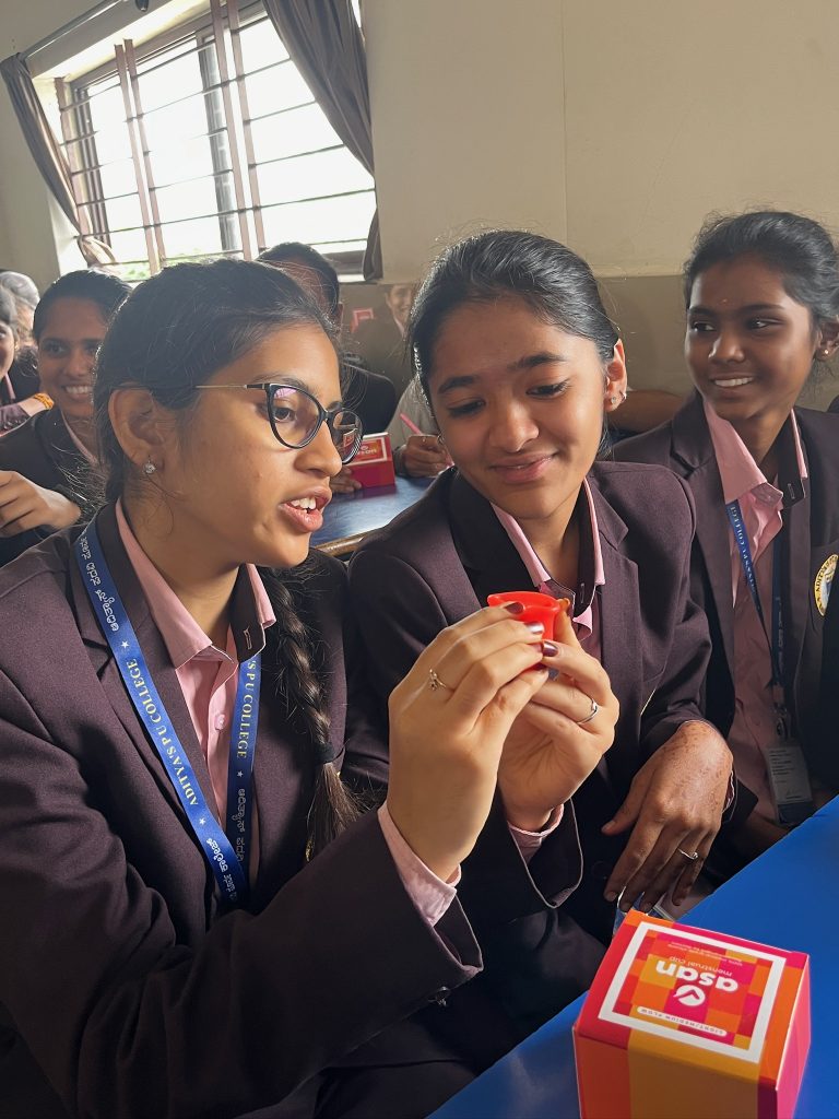 School girls holding a menstrual cup in their classrom 